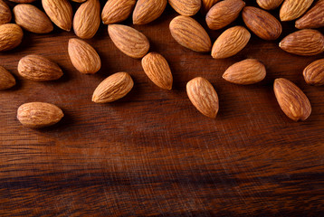 Almonds on textured wooden background, top view. Copy space on down side
