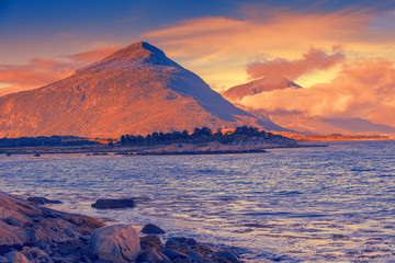 Fototapeta premium Arctic wilderness, mountain landscape at magic sunset, rocky sea shore. Beautiful fjord, pebbles sea shore. Nature Norway, Lofoten island