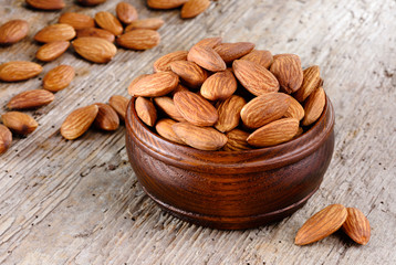 Shelled almonds in a bowl on wooden background. Organic food.