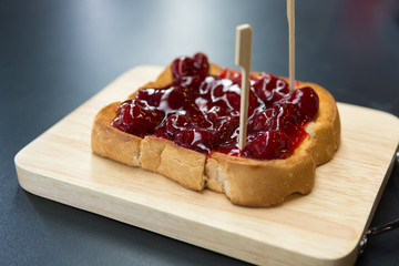 Strawberry jam toast on  wooden plate, Black background