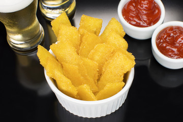 Fried polenta in a ramekin in black background seen from above