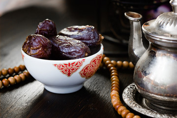 Ramadan fasting - dates for iftar in bowl on wooden table.
