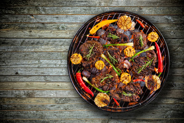 Top view of fresh meat and vegetable on grill placed on wooden floor