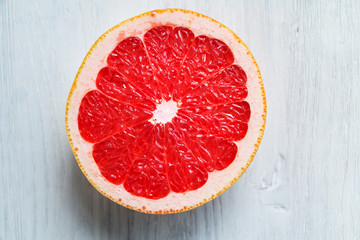 Half of grapefruit, red, ripe, top view on white wooden table. Copy space.