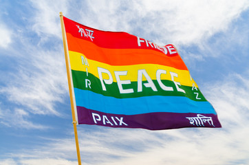 Rainbow multiolored peace flag wind flying against blue sky