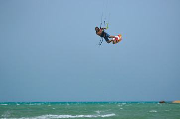 Fototapeta premium Professional kite boarding rider sportsman jumps high acrobatics kiteboarding trick with raley from water. Recreational activity and extreme active water sports, hobby and fun time
