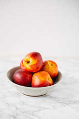 Ripe peaches in bowl on marble background
