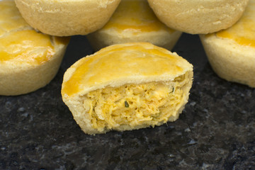 Traditional mini chicken pie called empadas with one open in granite platter