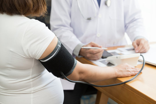 Doctor examining pregnant woman and pressure measurement with a detector