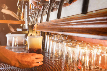 Bartender hand pouring draught beer to glass from a pub tap