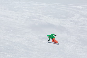 Male snowboarder snowboarding on fresh snow on ski slope on Sunny winter day in the ski resort in...