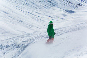 Male snowboarder snowboarding on fresh snow on ski slope on Sunny winter day in the ski resort in...