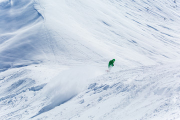 Male snowboarder snowboarding on fresh snow on ski slope on Sunny winter day in the ski resort in...