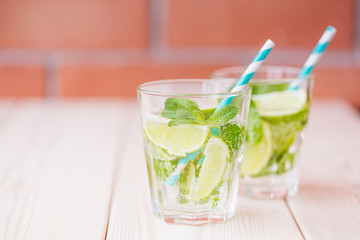 Two fresh mojitos cocktail in glass on wooden table. Mojitos with mint leaves, lime and ice.