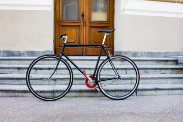 Fototapeta na wymiar vintage single speed bicycle near the stairs and old wooden door