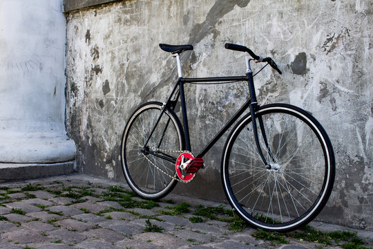 black hipster bicycle near the grey concrete wall