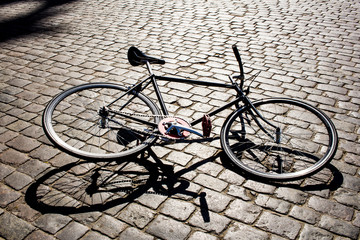 Fototapeta na wymiar black fixedgear bicycle on cobbles road in sunset light