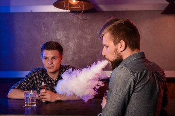 Two young men smoke electronic cigarettes in a vapebar