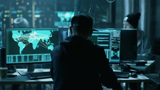 Team of Internationally Wanted Hackers Teem Organize Advanced Virus Attack on Corporate Servers. Place is Dark and Has Multiple displays. Shot on RED EPIC-W 8K Helium Cinema Camera.