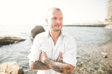 handsome model man posing on stone by the sea