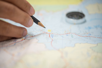 man's hand holding a pencil to writing on map