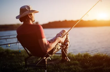 Zelfklevend Fotobehang Men fishing in sunset and relaxing while enjoying hobby © NDABCREATIVITY