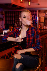 Young pretty woman smoke an electronic cigarette at the vape bar