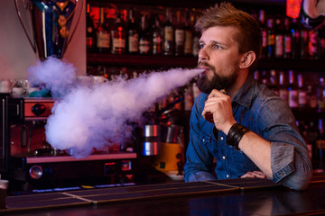 Vape. Vaping man in a cloud of vapor. Photo is taken in a vape bar.