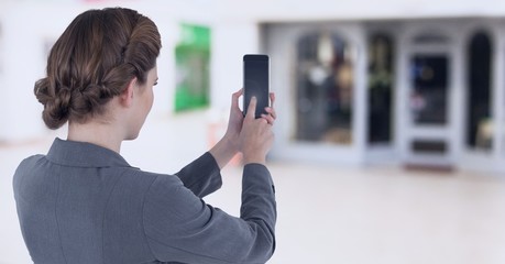 Businesswoman holding mobile phone in shopping mall
