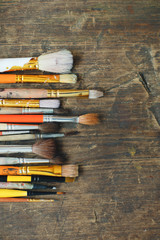 row of artist paintbrushes closeup on old wooden rustic table
