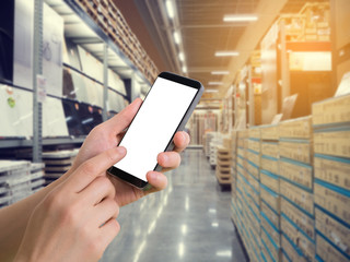 human hand hold smartphone, tablet, cell phone on blurry storehouse, concept of Ordering product online.
