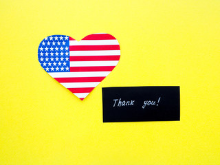 Obraz premium Thank you sign on a chalkboard with American flag on yellow background, USA