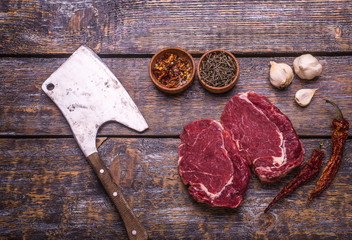 Raw Beef Steak, salt, pepper, garlic, rosemary  on the wooden board, background.