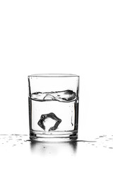 Cube of ice thrown into a glass with liquid