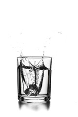 Cube of ice thrown into a glass with liquid