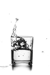 Cube of ice thrown into a glass with liquid
