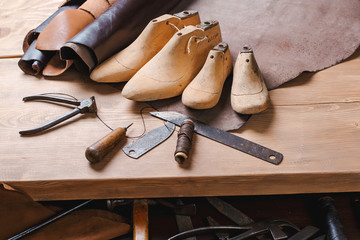 Leather in rolls, cobbler tools and shoe lasts in workshop. Leather craft tools.
