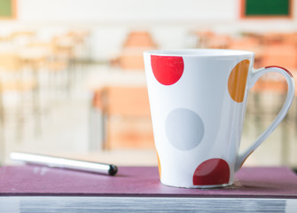 White and red cup coffee on book,  blur desk classroom background in school, pastel tone