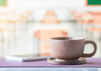 wood cup coffee on book with blur on desk classroom background, pastel tone