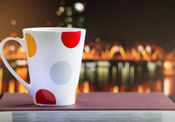 White and red cup coffee on book, views blur night light background