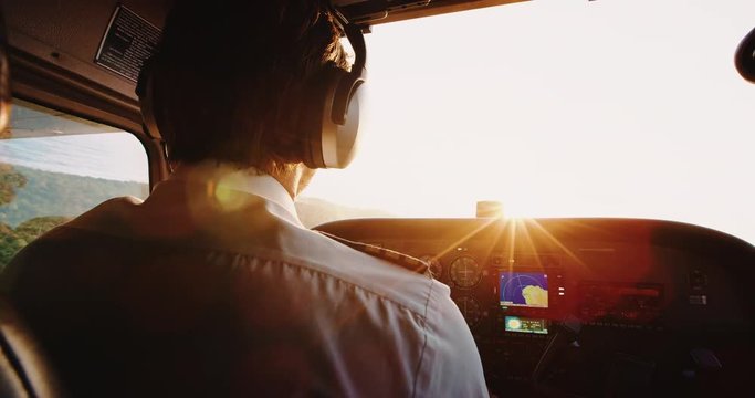 Pilot flying airplane. Bank turn into sunrise golden morning light. POV view from inside cockpit
