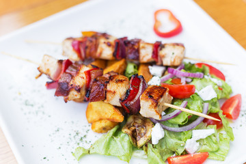 Grilled skewers with vegetables and meat in a herb marinade isolated on white plate.