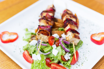 Grilled skewers with vegetables and meat in a herb marinade isolated on white plate.