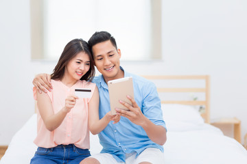 Happy Family,Asian couple lovers enjoy using smart tablet for shopping online together in bedroom.