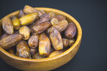 Close up of a plate of dried dates on a black  background.