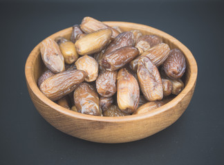 Close up of a plate of dried dates on a black  background.