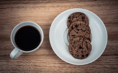 Mug of coffee with cookies on wooden table