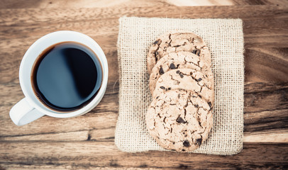 Mug of coffee with cookies on wooden table