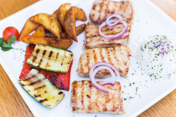 Grilled chicken with grilled vegetables on white plate.