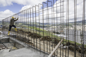 Fototapeta premium obrero trabaja en construcción en edificio de estructura en las alturas